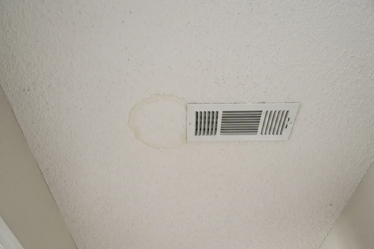 A faint tea-colored ring on a white ceiling directly below an air handler closet