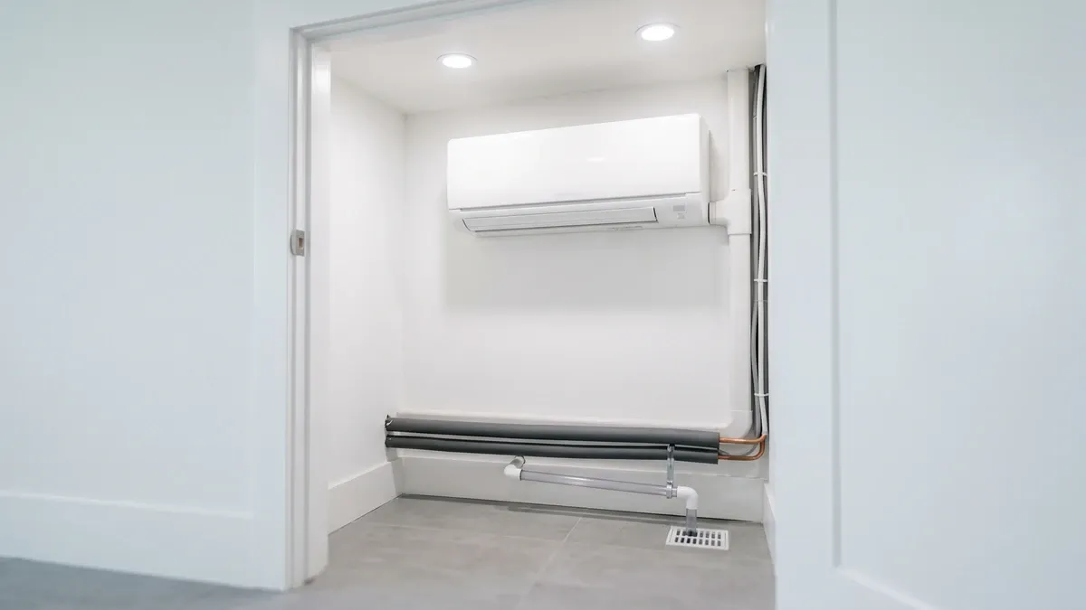 Residential AC air handler unit mounted in a utility closet with PVC condensate drain pipe at the base — the type of system where condensate clogs seed HVAC mold in Phoenix homes.